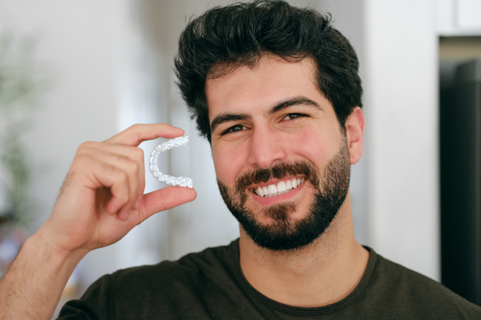 Adult holding a clear retainer to help keep teeth from shifting in Bellevue WA